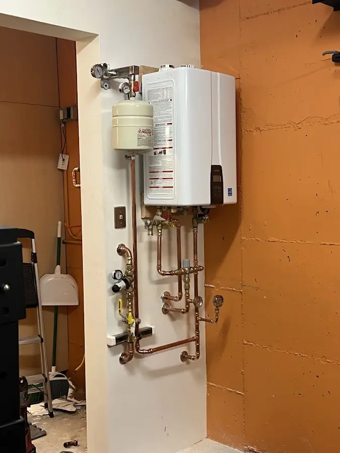 Plumbing technician inspecting water heater connections in Wonder Lake